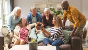 A group of friends share laughter over the contents shown on a tablet.