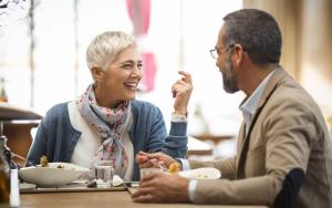Two older adults talking and laughing in restaurant.