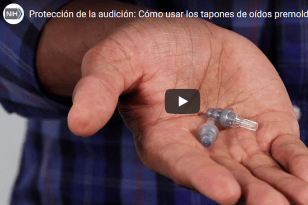 Un  hombre que muestra la forma correcta de usar tapones de oídos premoldeados para ayudar a prevenir la pérdida de audición inducida por el ruido.