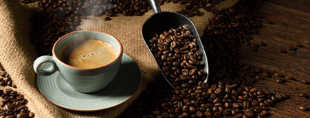 A cup of coffee and a scoop of coffee beans.